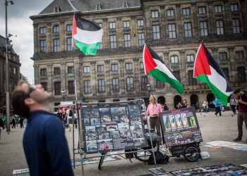 People look at a BDS stand with photos and Palestinian flags, calling to 'Free Palestine' at Dam Square in central Amterdam, Holland, on June 24, 2016. Photo by Hadas Parush/Flash90 *** Local Caption *** àîñèøãí
äåìðã
àéøåôä
úééøåú
úééøéí
èéåì
çøí
áé ãé àñ
ôìñèéï
ôìñèéðéí
éùøàì
ôøå ôìñèéðàé
àðèé éùøàì
éùøàìéí