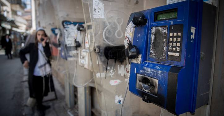 An Ultra Orthdox Jewish man uses a public pay phone in the street, in the ultra orthodox Mea Shearim neighbourhood in Jerusalem, on April 8, 2018. Photo by Yonatan Sindel/Flash90 *** Local Caption *** ??? ?????
????? 
?????? 
????
?????
???
??
???
???
???????
????
?????????
??????????
????
?????
??????
?????
???